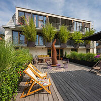 Modern eco-friendly hotel with a spacious wooden deck, comfortable outdoor seating, and lush potted plants